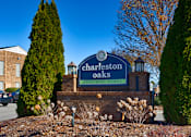 Thumbnail 61 of 62 - A sign for Charleston Oaks Apartment Homes is displayed in front of a building.