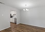 Thumbnail 35 of 46 - A kitchen with white walls and wooden floors is visible through a window.