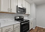 Thumbnail 37 of 46 - A kitchen with white cabinets and a black stove top oven.