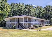 Thumbnail 1 of 46 - A large apartment complex with a green lawn in front.