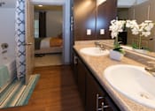 Thumbnail 91 of 91 - A bathroom with a sink, mirror, and a bed in the background.