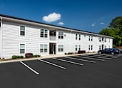Thumbnail 2 of 46 - a large white building with a car parked in front of it