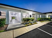Thumbnail 10 of 46 - the exterior of a white building with a driveway and landscaping