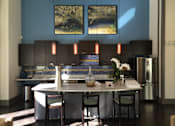 Thumbnail 23 of 91 - A kitchen with a blue wall and a painting hanging above the counter.