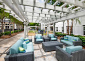 Thumbnail 12 of 57 - A patio with a white pergola and grey wicker furniture.