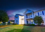 Thumbnail 3 of 36 - a row of houses with a green yard and a cloudy sky