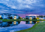 Thumbnail 1 of 36 - a pond in front of a row of houses at sunset
