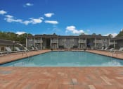Thumbnail 5 of 39 - Apartments Near Region Field - MarQ Vestavia - Pool With Grey Sun Lounge Chairs, Brick-Style Flooring, Blue Sun Umbrella, And View Of Apartment Complex