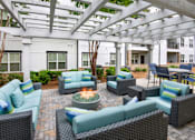 Thumbnail 25 of 57 - A patio with a fire pit and wicker furniture.