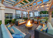 Thumbnail 26 of 57 - A patio with a fire pit and seating area.