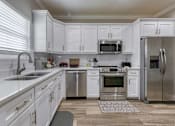 Thumbnail 21 of 47 - A kitchen with white cabinets and stainless steel appliances.