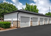 Thumbnail 28 of 57 - A white building with a black roof and four garage doors.