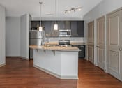 Thumbnail 62 of 91 - A kitchen with a white island and wooden floors.