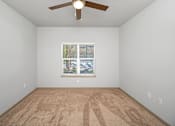 Thumbnail 67 of 91 - A room with a ceiling fan and a window with a view of a parking lot.