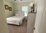 Thumbnail 40 of 47 - A bedroom with a bed, a dresser, and a ceiling fan.