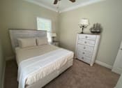 Thumbnail 41 of 47 - A bedroom with a bed, dresser, and ceiling fan.