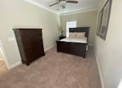 Thumbnail 42 of 47 - A bedroom with a bed, dresser, and ceiling fan.
