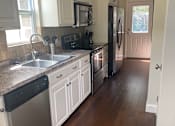 Thumbnail 39 of 47 - A kitchen with white cabinets and a black fridge.