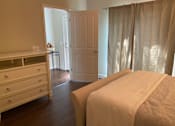 Thumbnail 44 of 47 - A bedroom with a bed, dresser, and window with curtains.
