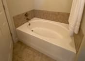 Thumbnail 47 of 47 - A white bathtub in a bathroom with a picture frame on the wall.