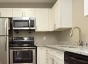 Thumbnail 21 of 39 - Townhomes In Vestavia, AL - MarQ Vestavia - Kitchen Area With White Cabinets, Granite-Style Countertops, And Stainless-Steel Appliances