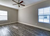 Thumbnail 25 of 46 - A room with a ceiling fan and wood flooring.