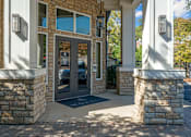 Thumbnail 30 of 91 - A building entrance with a stone pillar and a black mat.