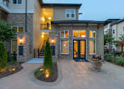 Thumbnail 32 of 91 - A modern house with a stone facade and a lit up entrance.