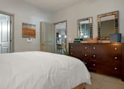 Thumbnail 88 of 91 - A bedroom with a white bed and a wooden dresser.
