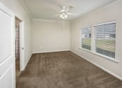 Thumbnail 39 of 50 - an empty living room with carpet and a ceiling fan