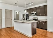 Thumbnail 43 of 91 - A kitchen with a white island and wooden floors.