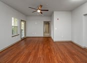 Thumbnail 38 of 91 - A room with a ceiling fan and wooden floors.