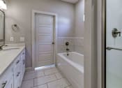 Thumbnail 29 of 47 - A white bathroom with a tub, sink, and shower.