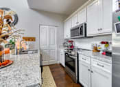 Thumbnail 22 of 47 - A kitchen with white cabinets and a marble countertop.