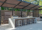 Thumbnail 17 of 91 - A wooden bar with a concrete counter and stools under a roof.