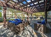 Thumbnail 14 of 91 - A wooden pergola with blue cushions and a concrete floor.