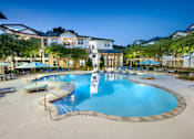 Thumbnail 19 of 57 - A large swimming pool surrounded by lounge chairs and umbrellas at a resort.