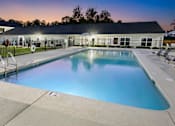 Thumbnail 31 of 46 - a swimming pool with chairs and a building in the background