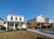 Thumbnail 6 of 47 - Two houses with front porches and a clear blue sky above.