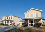 Thumbnail 8 of 47 - A yellow house with a porch and a covered driveway.
