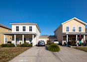 Thumbnail 9 of 47 - A residential street with two houses and cars parked in front.