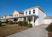 Thumbnail 14 of 47 - A white house with a grey garage door is in front of a row of houses.
