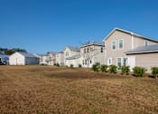 Thumbnail 5 of 47 - A row of houses with a brown grass field in front.