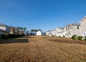 Thumbnail 11 of 47 - A grassy field with houses in the background.