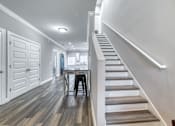Thumbnail 20 of 47 - A staircase with a wooden handrail and steps leading to a dining area with a table and chairs.