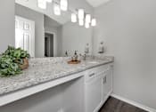 Thumbnail 36 of 62 - A bathroom with a marble countertop and white cabinets.