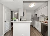 Thumbnail 27 of 62 - A kitchen with white cabinets and a white island.