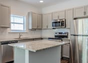 Thumbnail 33 of 47 - A kitchen with a granite countertop and stainless steel appliances.