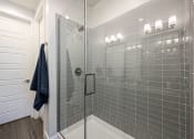 Thumbnail 49 of 73 - a bathroom with gray tiles and a glass shower door at Scottsdale Hayden Townhomes, Scottsdale, AZ, 85257