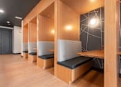 Thumbnail 29 of 81 - A row of wooden benches with black cushions are lined up in a room.